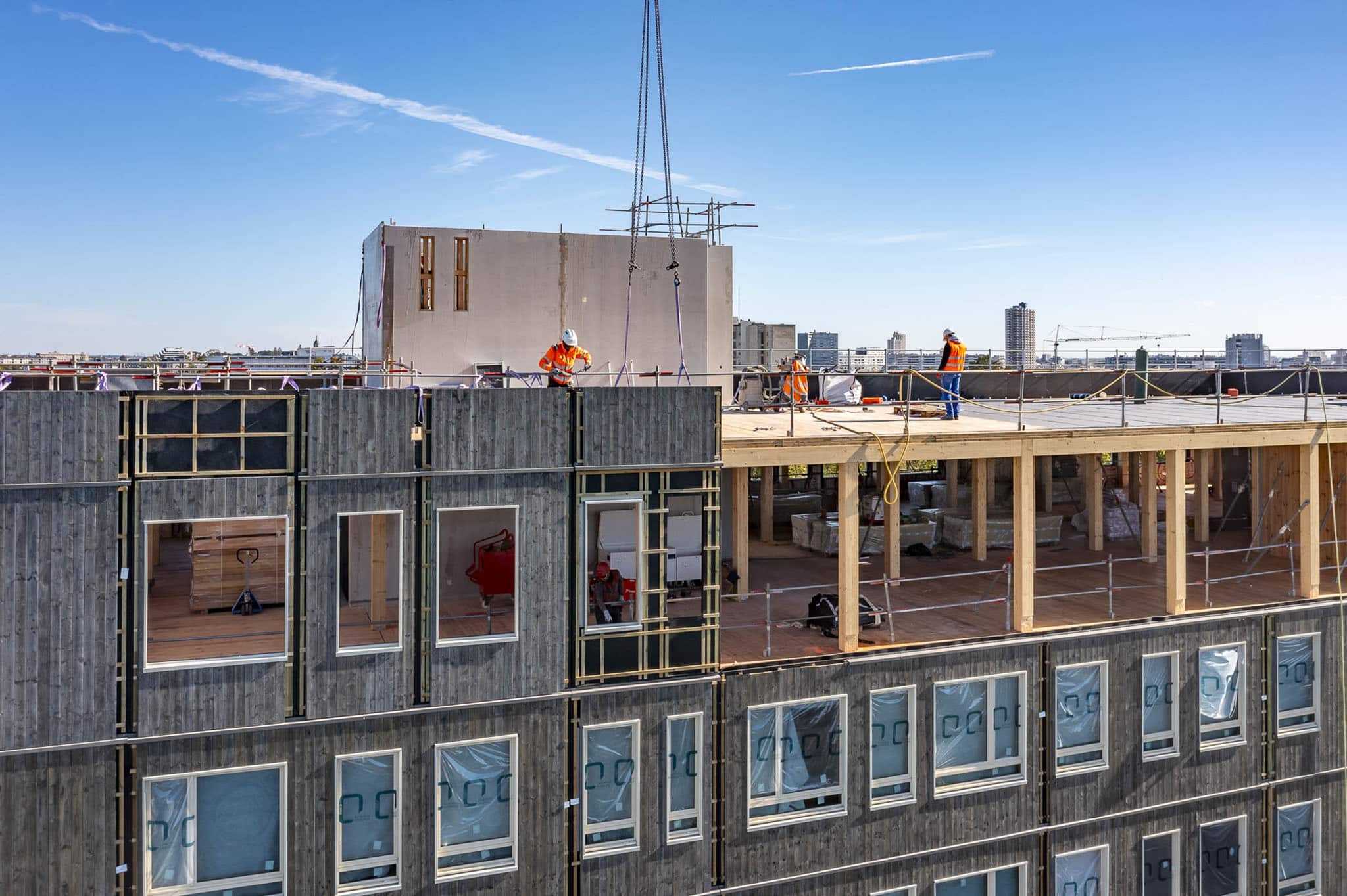 Bâtiment tertiaire au Centre Hospitalier Universitaire de Rennes, vue de la pose d'un module de façade en bois préfabriqué lors du chantier